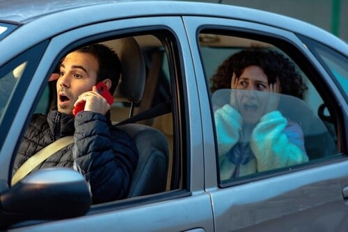 distracted driver talking on phone while alarmed passenger reacts in vehicle